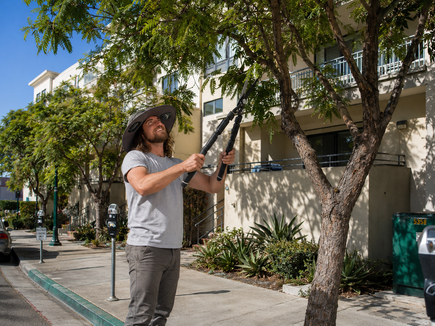 Jr trimming a street tree with hedge shears outside a downtown San Diego condo building